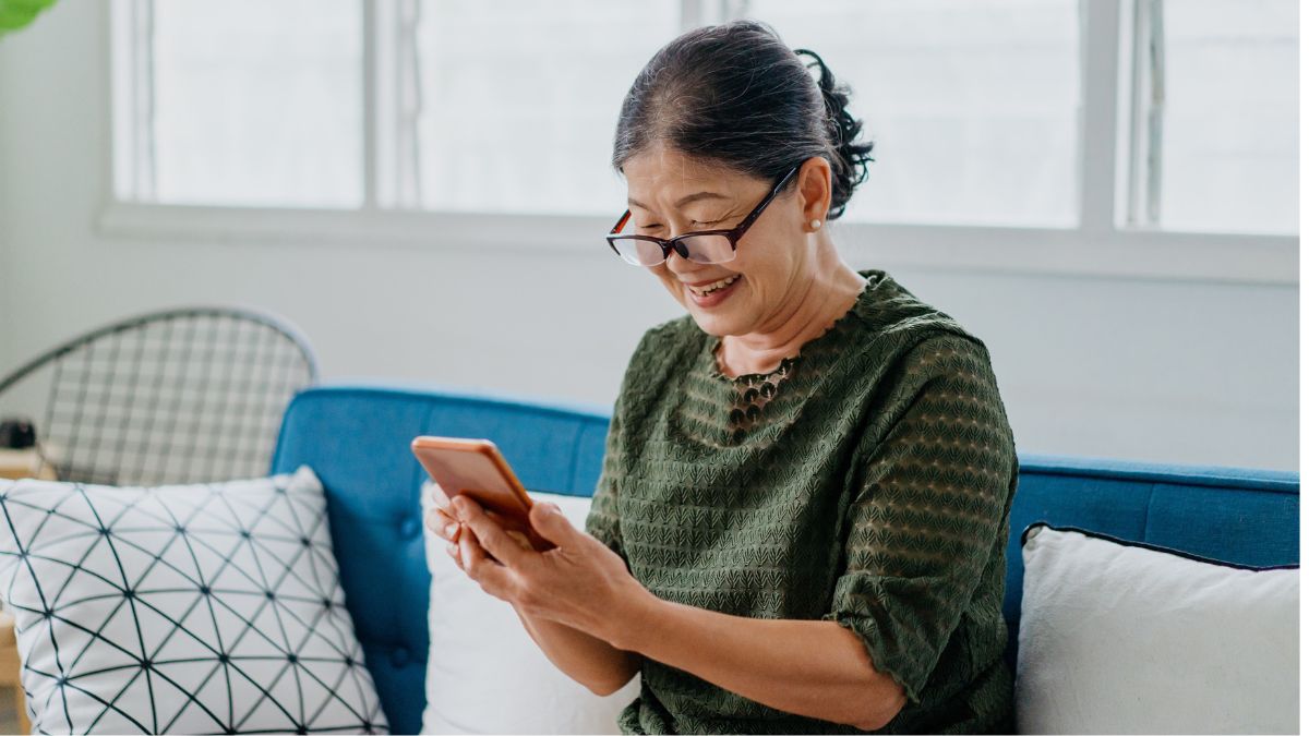 happy woman wearing glasses playing a game on her phone, which studies say could reduce breast cancer risk