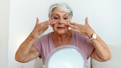 mature woman massaging her face in circles, beauty tips