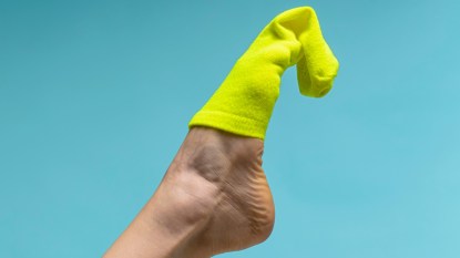 green sock half on a foot, concept for putting on socks without bending