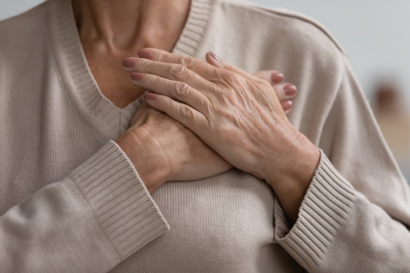 Close up cropped image of hopeful mature woman with her hands on her heart