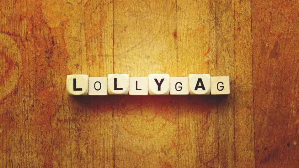 lollygag spelled out on wooden surface, concept for word origins