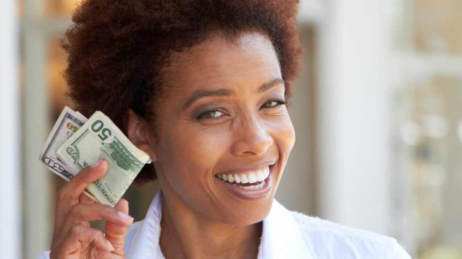 mature woman smiling and holding 50 dollar bills