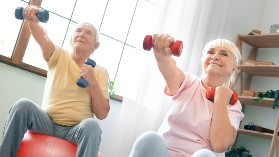 senior couple doing a weight training routine with red and blue dumbbells