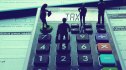 Miniature people walking on calculator on top of tax papers