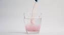 Pouring instant drink purple colour powder in glass of water