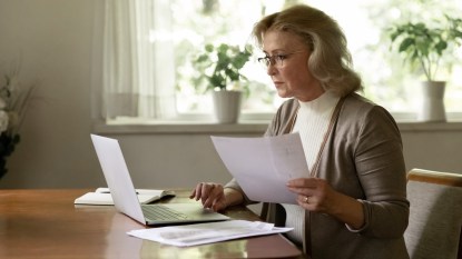 Woman using laptop and looking at papers