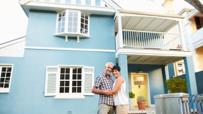 Man and woman posing in front of house