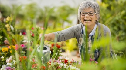 Woman smiling as she waters flowers in garden