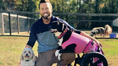 Derrick Campana smiling with two dogs, prosthetics for animals