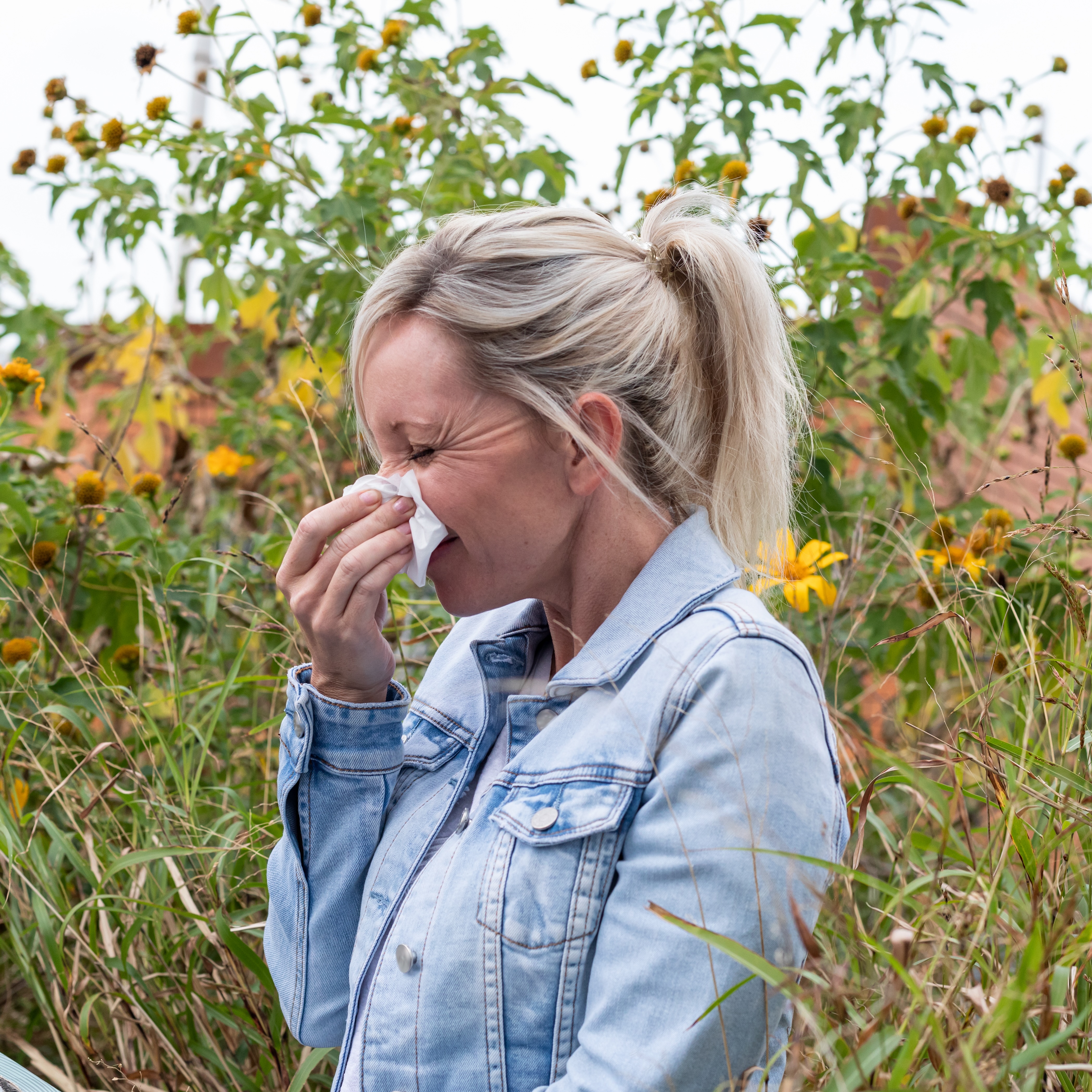 Woman sneezing in the flowers