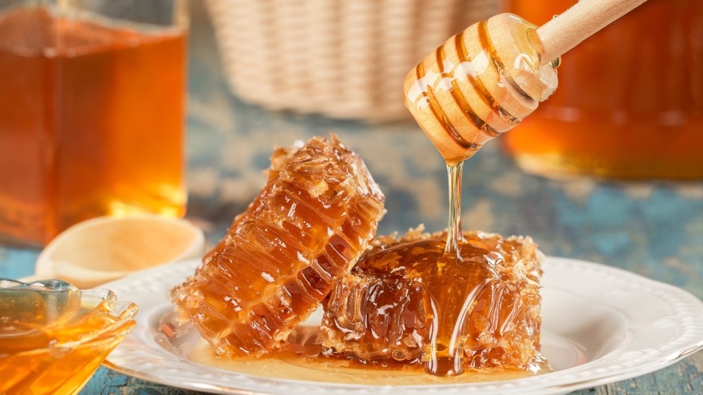 A honey dipper drizzling honey over fresh honeycombs, which has benefits for women