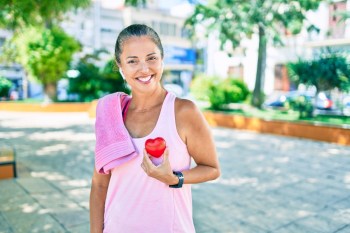 Woman holding red heart shaped object over her heart