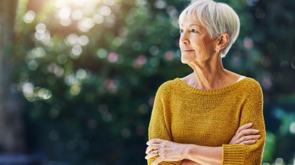 mature woman with short white hair gazing resolutely into the distance, arms folded