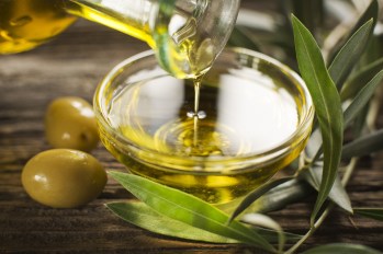 Bottle pouring olive oil in a bowl close-up