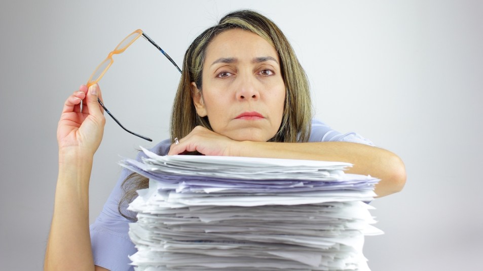 Woman leaning against big stack of papers
