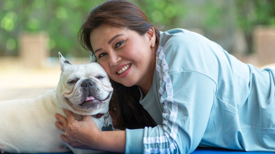Middle-aged Asian woman lying and relaxing with her dog, looking at camera