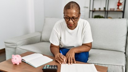 Woman filling out paperwork with notebook and calculator