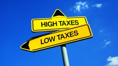 Sign with "High Taxes" and "Low Taxes" in front of blue sky