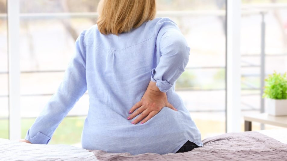 Senior woman with back pain sitting on bed
