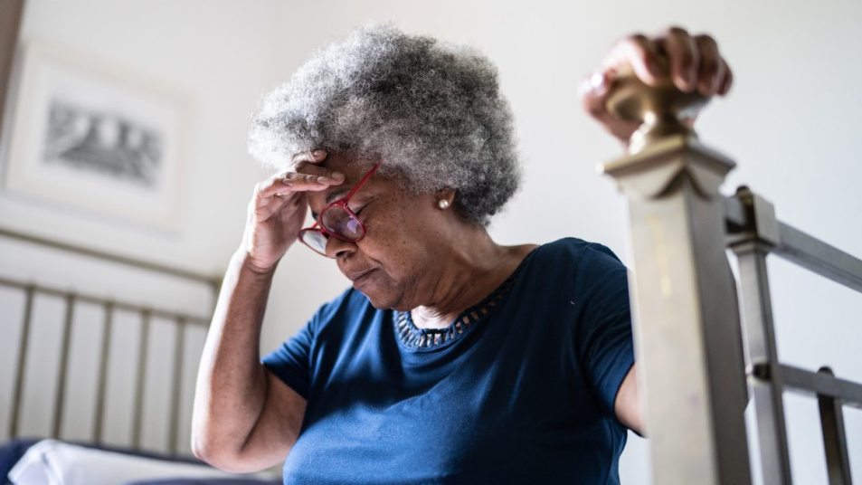 Senior woman with glasses struggling with brain fog, hand to her head