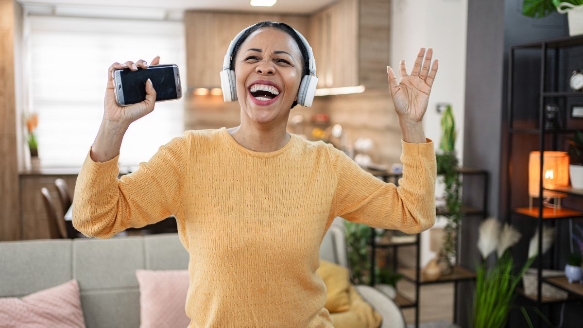 woman wearing headphones dancing to music smiling to improve circulation