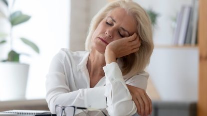 mature woman falling asleep at desk, menopause insomnia concept
