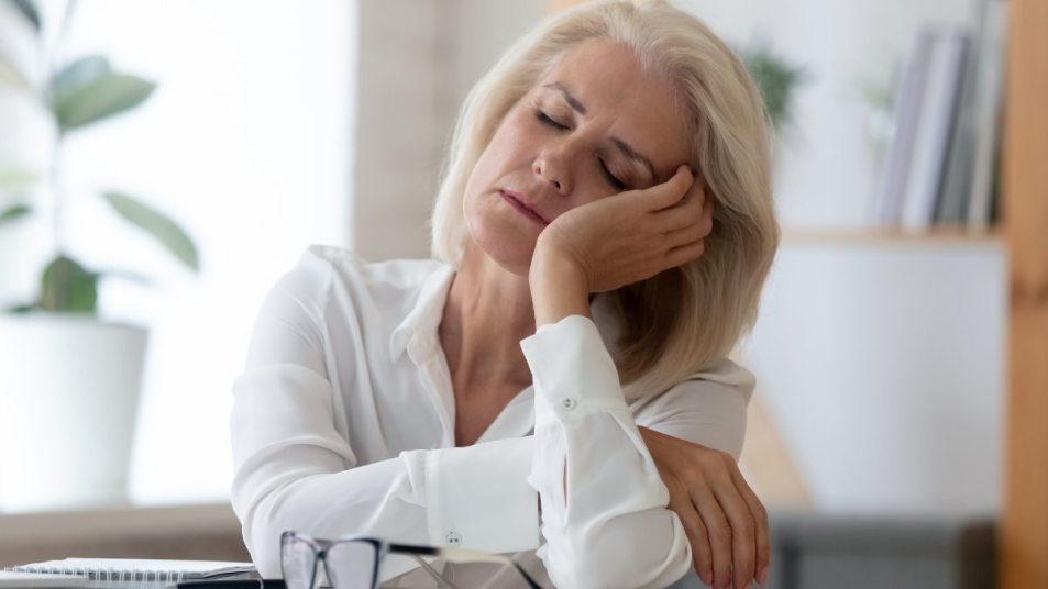 mature woman falling asleep at desk, menopause insomnia concept