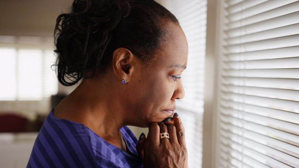 senior woman gazing out window, mental health guidance concept