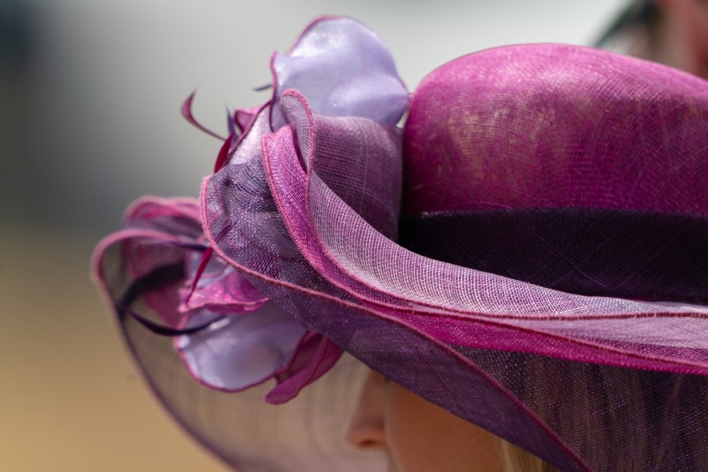 Woman wearing fancy purple bowler hat with ribbons
