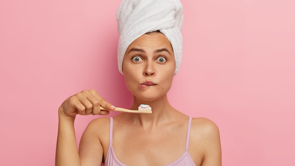 Woman brushing her teeth looking surprised