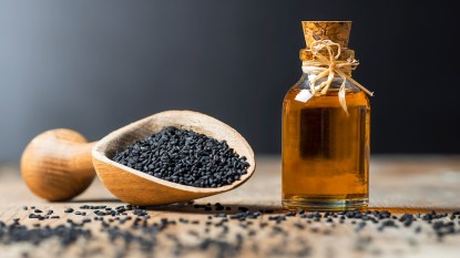 Black cumin seeds and glass bottle of black seed oil
