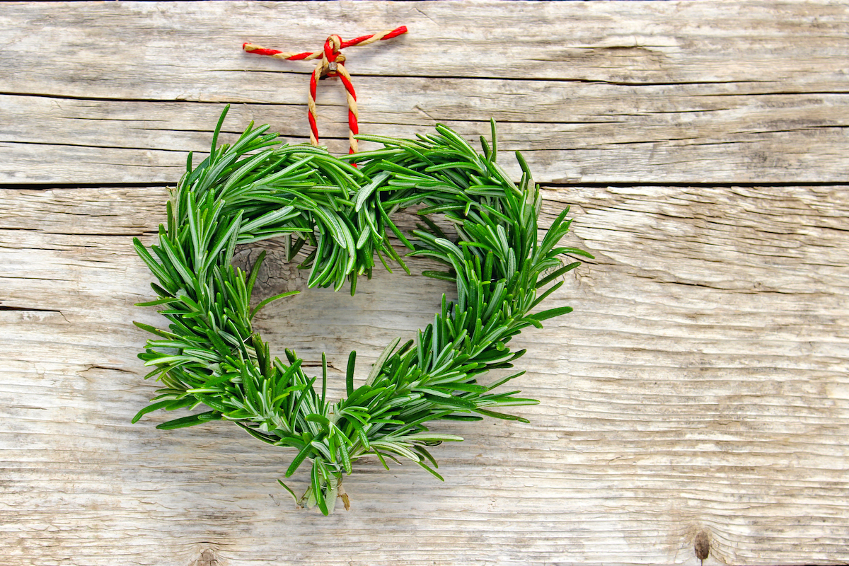 Heart shaped wreath made from rosemary hanging on a wooden wall