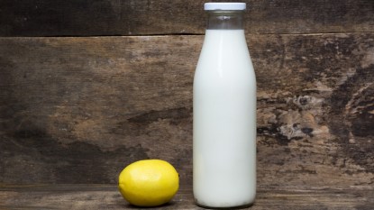 Glass bottle of milk with lemon next to it