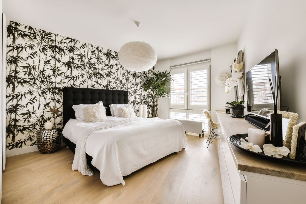 Comfortable,Bed,With,White,Blanket,And,Cushions,Placed,Near,Wall