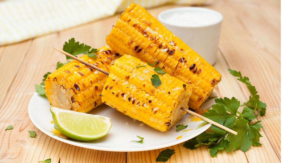 Corn on the cob with butter and herbs on a plate