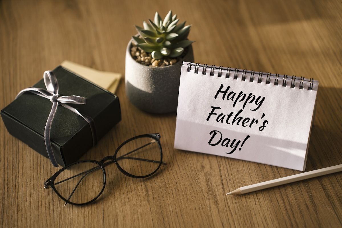 Father's Day holiday concept, phone with open calendar, glasses, note pads and pencils on the desk at home
