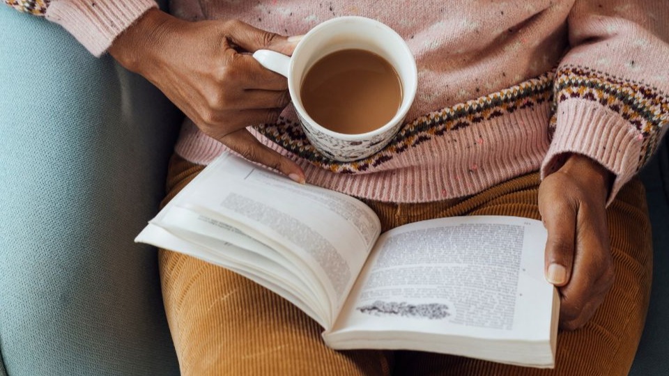 high angle view of a woman sitting reading a book with a hot drink