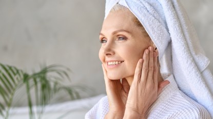 Mature woman smiling in bathrobe after shower or bath