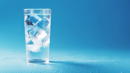 Glass of ice water against a blue backdrop that can help tone the vagus nerve