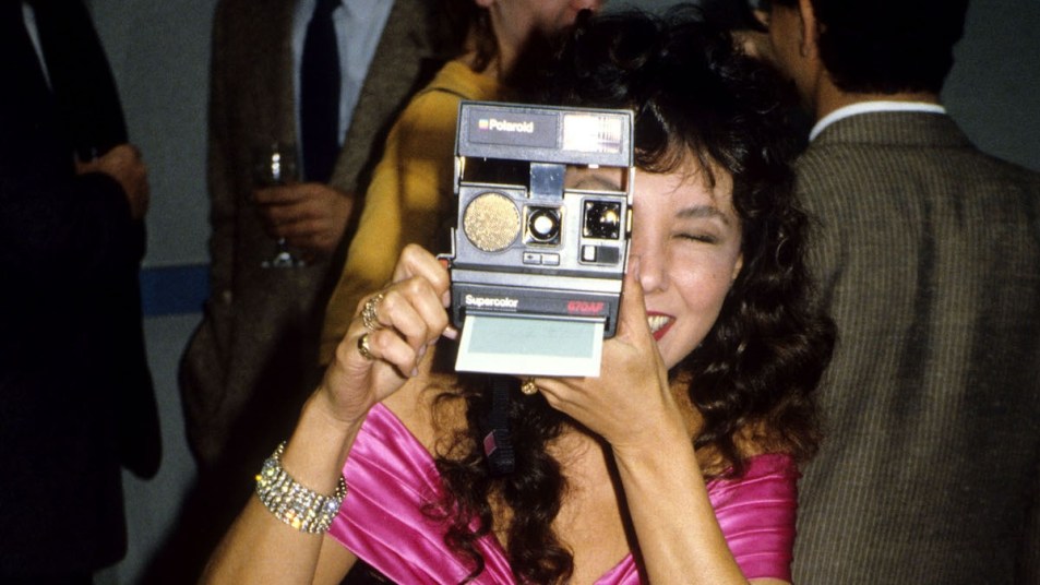 Model Marie Helvin Takes Pictures On Her Polaroid Camera in 1985