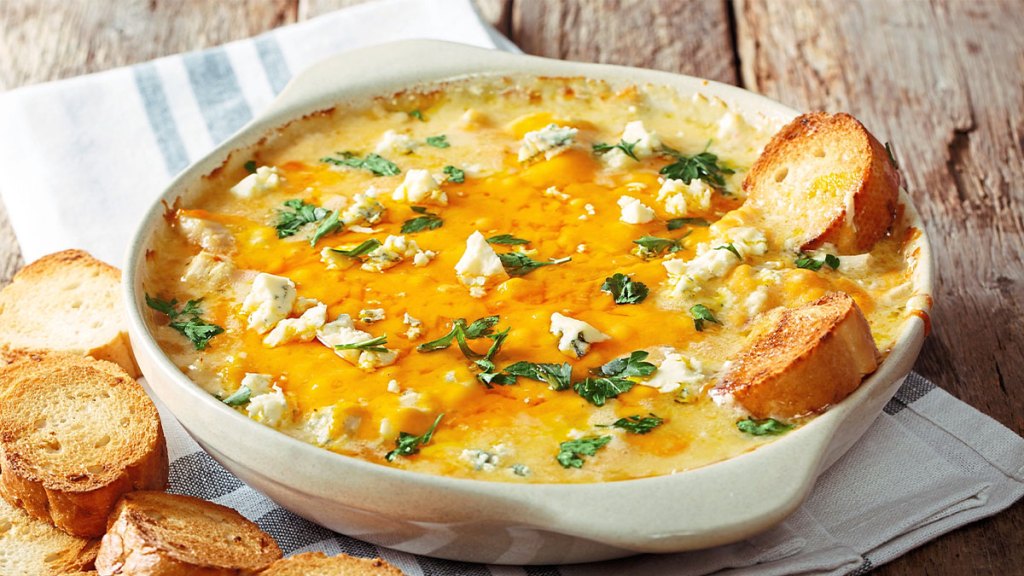 Buffalo chicken flavored dip in a bowl with slices of bread