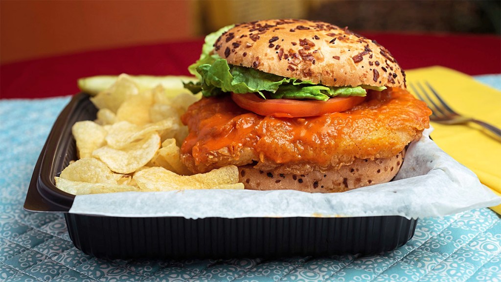 Buffalo chicken sandwich on a plate with potato chips