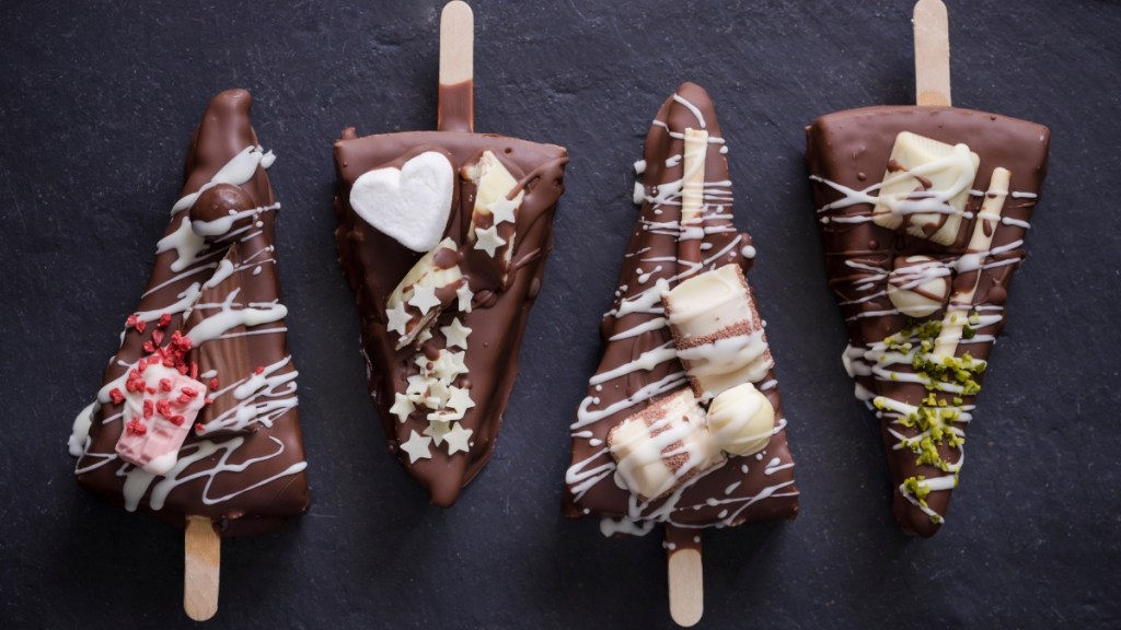 Chocolate covered cheesecake on a stick with toppings
