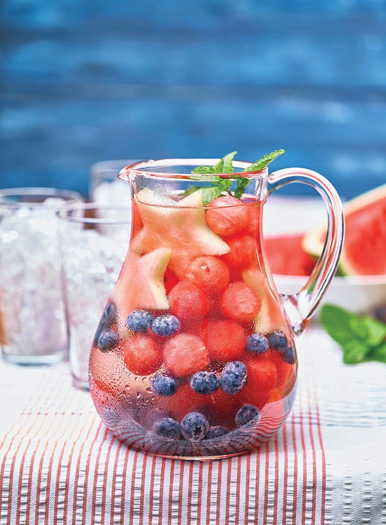 Clear pitcher filled with sangria with red and blue fruit