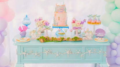 Mermaid Party Lead Tabletop Photo showing a pale teal tabletop filled with pastel-hued party accents and mermaid decorations