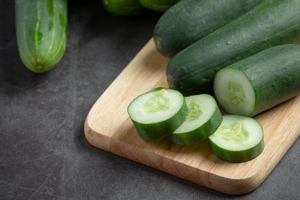 Cucumbers sliced up on cutting board.