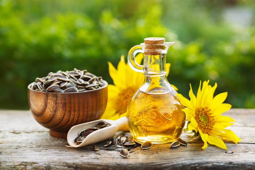 sunflower oil in a small glass jar with sunflower seeds and fresh flowers.