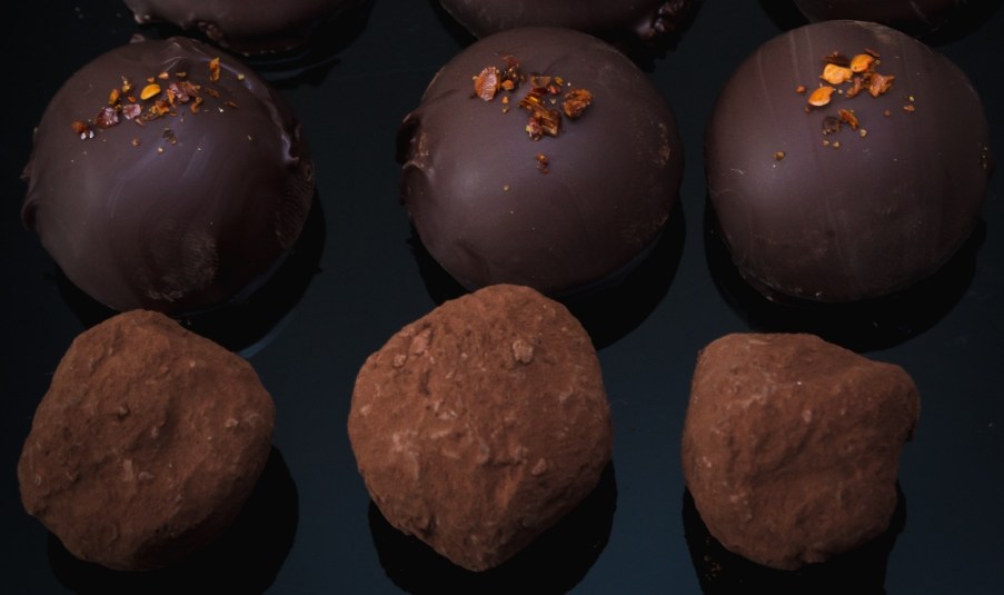 Rows of chocolate truffles on a dark background