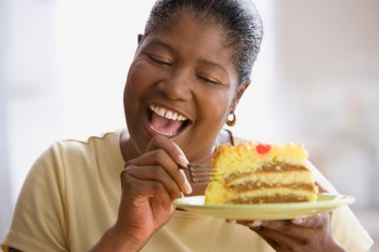 Middle-aged woman cutting into a slice of cake