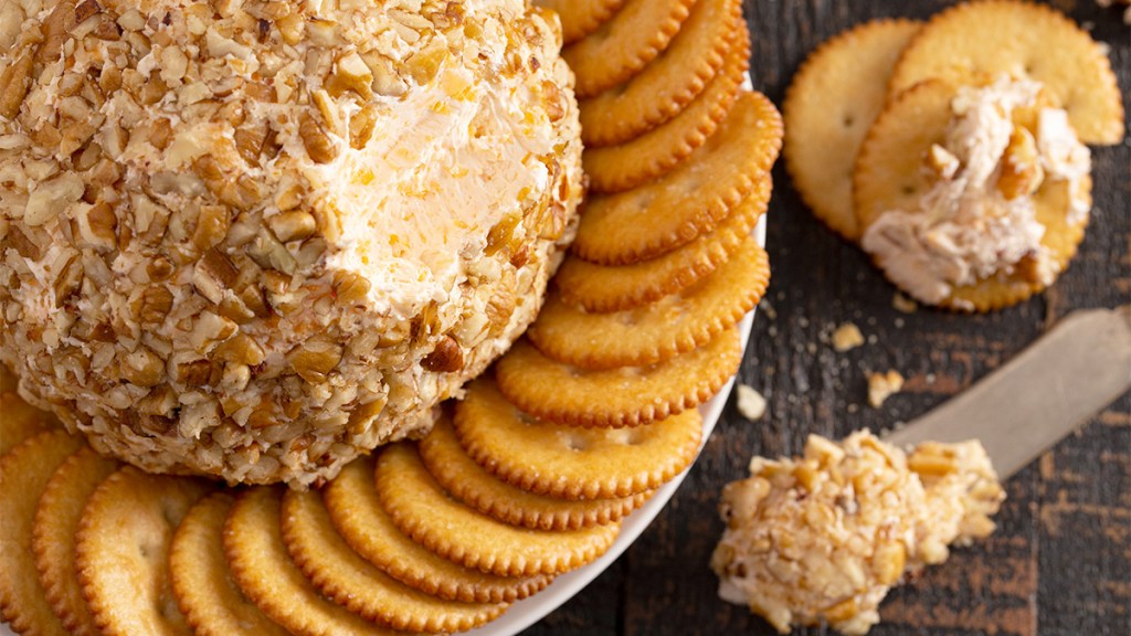 A cheese ball served with ritz crackers at a party.